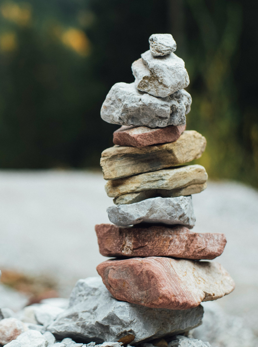 Steintürmchen aus 10 Steinen in verschiedenen Farben und Größen, Hintergrund natürlich und unscharf